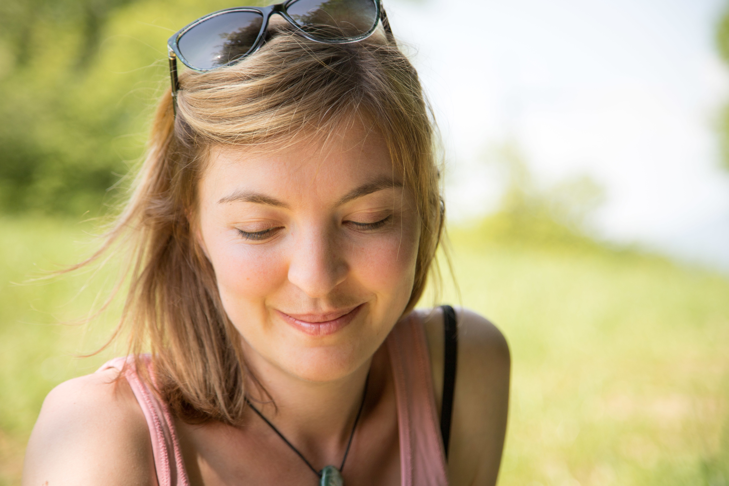 Junge Frau mit Sonnenbrille auf Sommerwiese, glücklich